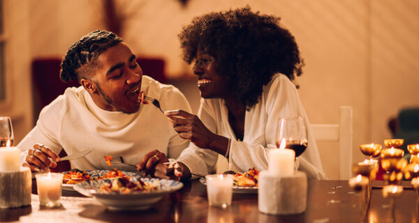 Eine Frau und ein Mann beim romantischen Candle-Light-Dinner, die ein Abendessen genießen.