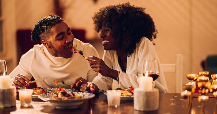 Eine Frau und ein Mann beim romantischen Candle-Light-Dinner, die ein Abendessen genießen.