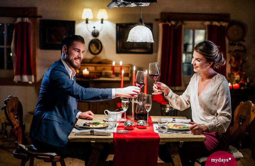 Candlelightdinner Paar stößt mit Weinglas an