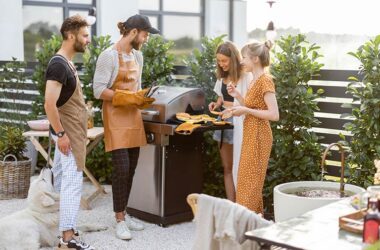 Freundesgruppe steht am Grill.