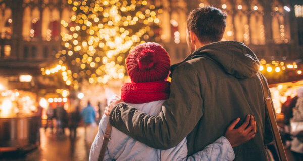 Pärchen schaut auf einen Weihnachtsbaum.