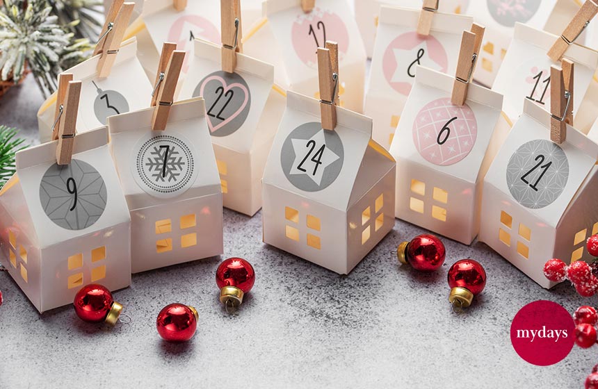 Ein selbstgebastelter Adventskalender mit kleinen Häuschen und kleinen Christbaumkugeln