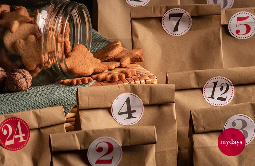 Adventskalender tütchen mit zaheln drauf. Daneben liegt ein Glas mit selbstgebackenen Keksen.