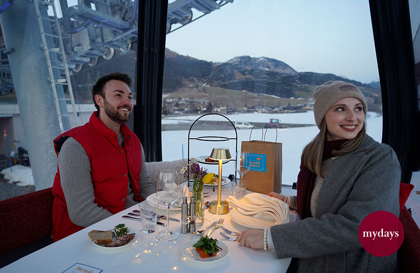 Zwei Personen vor einer winterlichen Landschaft in einer Gondel