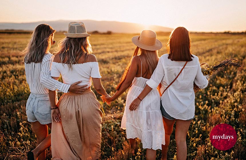 Vier Freundinnengheen über ein Feld bei Sonnenuntergang