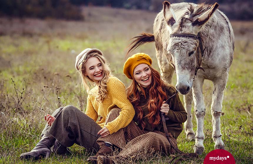 Zwei Mädchen genießen einen entspannten Ausflug mit einem Esel - eine wunderbare Geschenkidee für Entspannung vom Alltag.