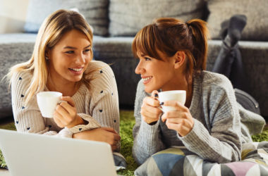 Zwei Frauen mit Kaffeetassen planen am Laptop