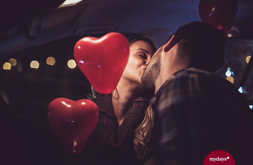Paar küsst sich Herzluftballons