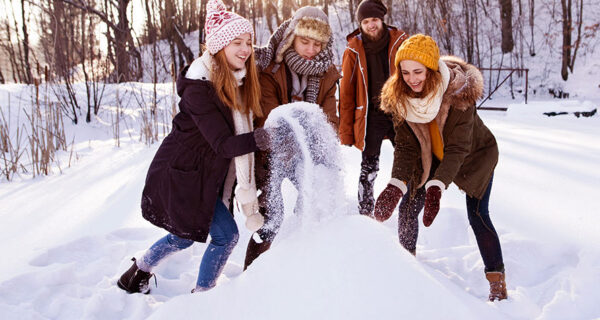 vier Freunde bauen einen Schneemann oder eine Schneebar
