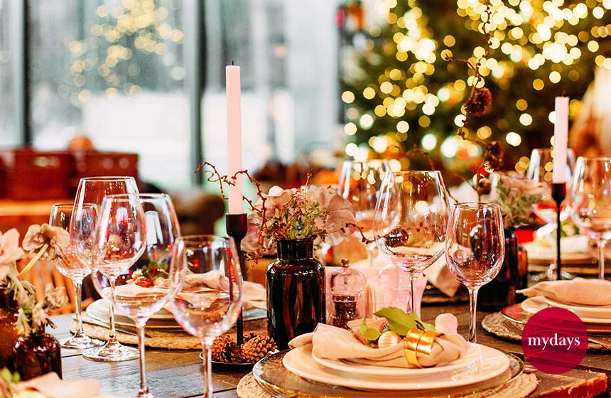 Ein gedeckter Tisch mit Weingläser und einem Tannenbaum m Hintergrund.