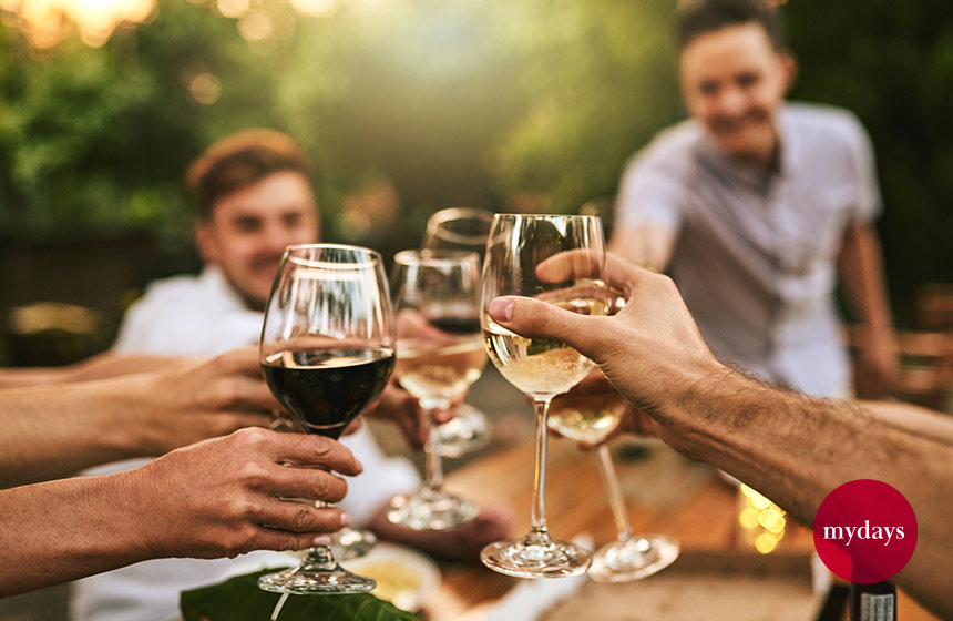 Eine Gruppe von Menschen stoßen zusammen mit einem Glas Wein zusammen an.