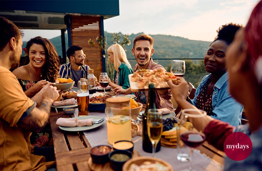 Fröhliche Freunde, die eine Mahlzeit am Esstisch auf einer Terrasse genießen