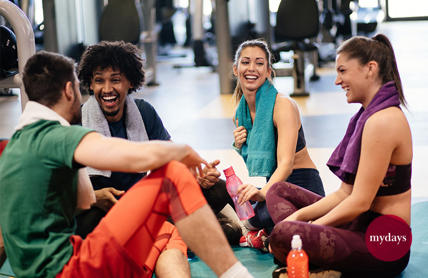 Junge fröhliche Menschen ruhen sich aus dem Training im Fitnessstudio und reden