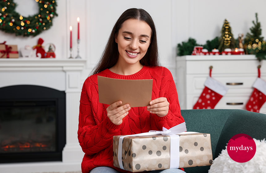 Junge Frau liest Karte, auf der Weihnachtssprüche besinnlich formuliert wurden